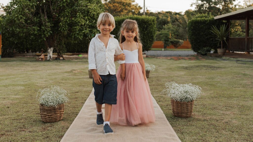 chłopiec i dziewczynka idą za rękę na ślubie